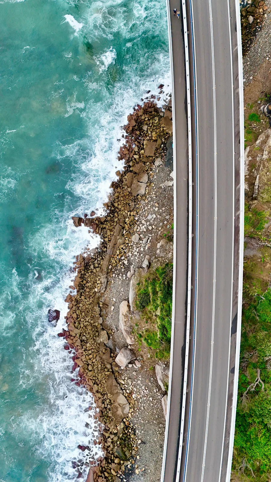 Drone aerial of the iconic Sea Cliff Bridge winding along the Grand Pacific Drive coastline south of Sydney